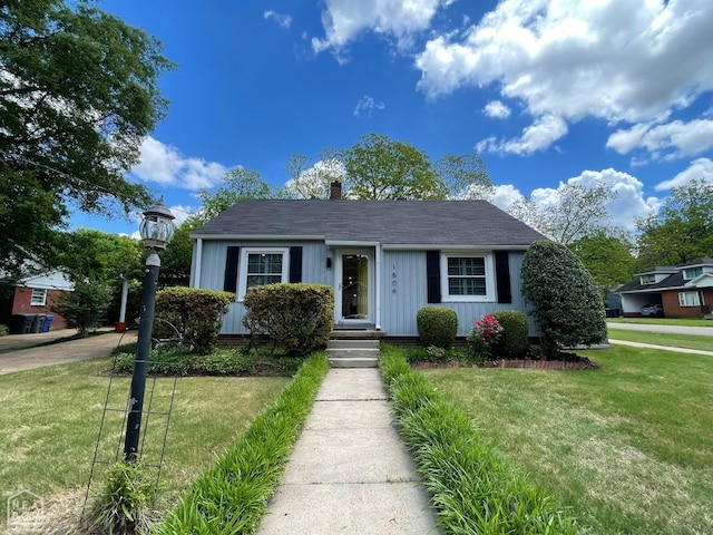 bungalow-style house with board and batten siding, a chimney, and a front yard