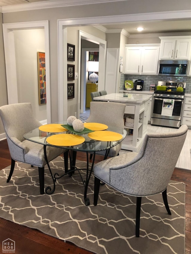 dining area featuring ornamental molding and wood finished floors