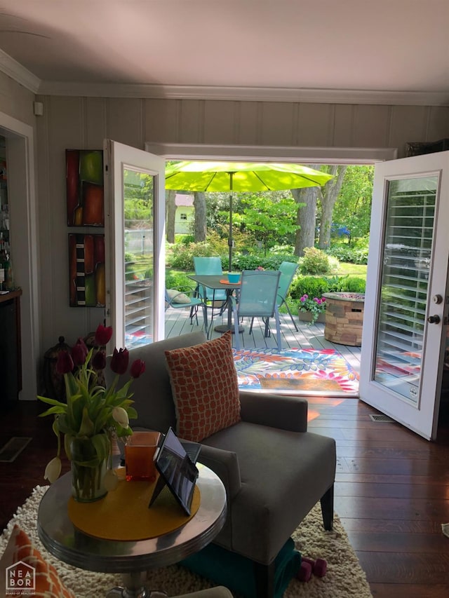 doorway featuring hardwood / wood-style floors, a decorative wall, crown molding, and plenty of natural light