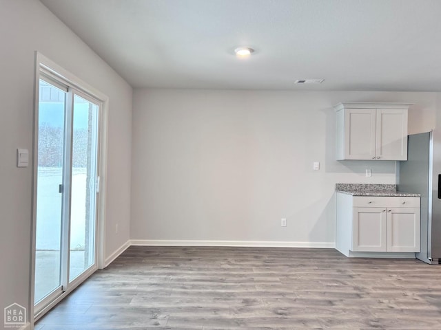 112 Terry Dr, Brookland, AR 72417 - kitchen featuring white cabinets, light wood-style floors, baseboards, and stainless steel fridge