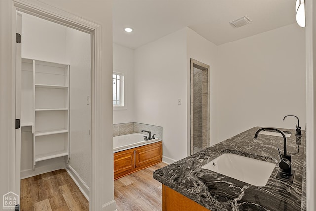 610 Airport Rd, Jonesboro, AR 72405 - full bath with wood finished floors, double vanity, a bath, baseboards, and a walk in closet