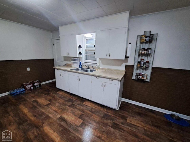 kitchen with light countertops, dark wood-type flooring, a sink, and white cabinetry