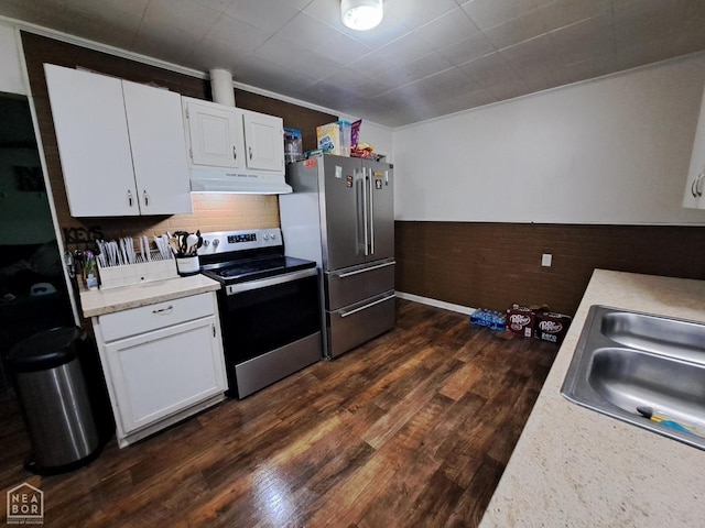 kitchen with dark wood-style flooring, light countertops, appliances with stainless steel finishes, under cabinet range hood, and wainscoting