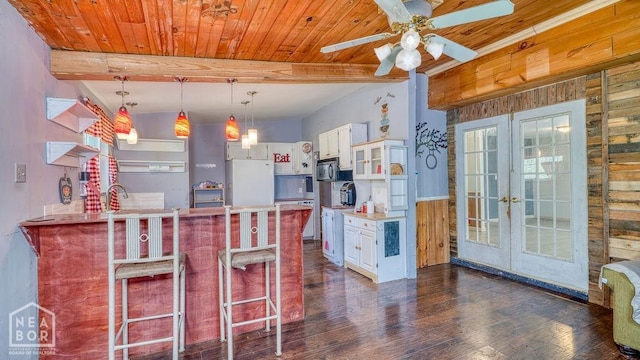 kitchen featuring black microwave, french doors, white cabinets, wood walls, and freestanding refrigerator