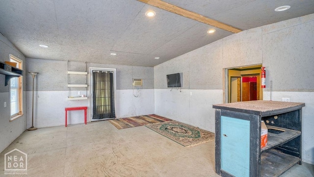 interior space with lofted ceiling, a wall mounted AC, concrete flooring, and recessed lighting