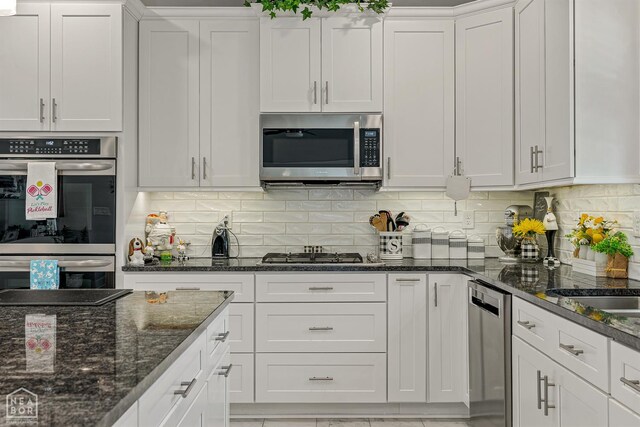 1502 S 30th St S, Paragould, AR 72450 - kitchen featuring appliances with stainless steel finishes, white cabinetry, tasteful backsplash, and dark stone countertops