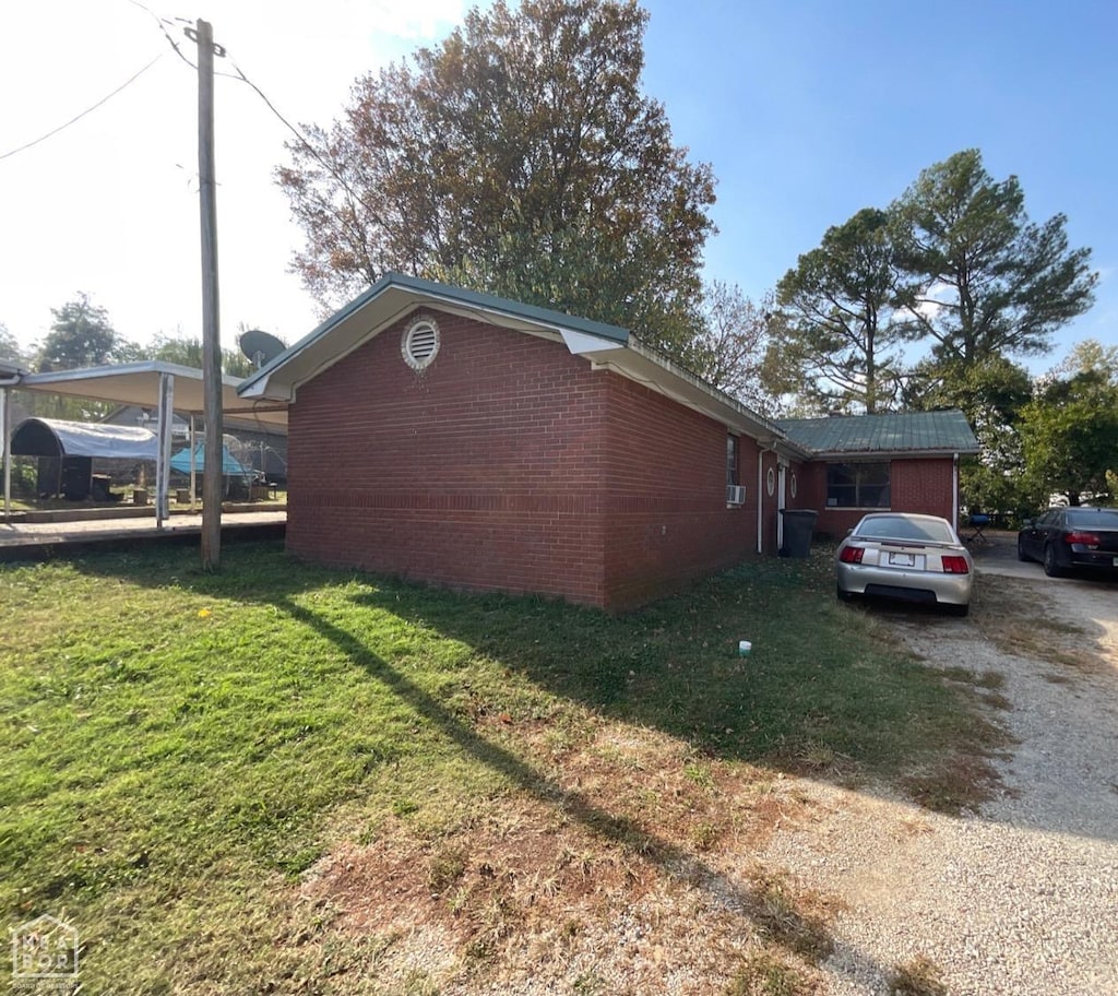 view of property exterior with a yard, brick siding, and driveway