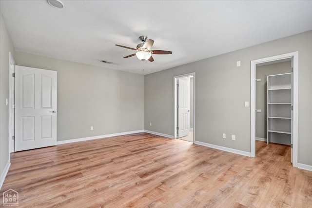 301 Natchez Dr, Jonesboro, AR 72404 - unfurnished bedroom featuring light wood-style flooring, a walk in closet, baseboards, and a ceiling fan