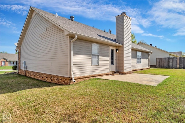 301 Natchez Dr, Jonesboro, AR 72404 - back of property featuring roof with shingles, a chimney, a patio area, fence, and a lawn