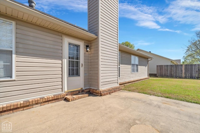 301 Natchez Dr, Jonesboro, AR 72404 - doorway to property featuring a chimney, a patio area, fence, and a yard