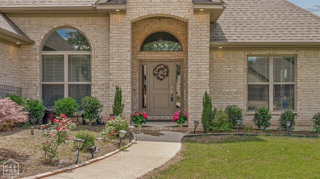 6605 Evan Cv, Jonesboro, AR 72404 - doorway to property with brick siding, a shingled roof, and a lawn
