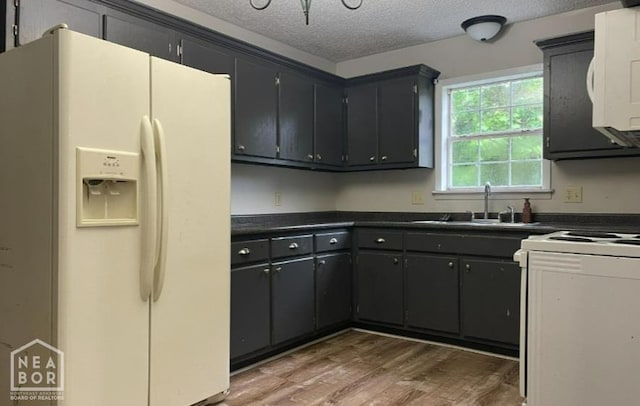 313 Olive St, Trumann, AR 72472 - kitchen with white fridge with ice dispenser, dark countertops, a textured ceiling, wood finished floors, and range with electric stovetop