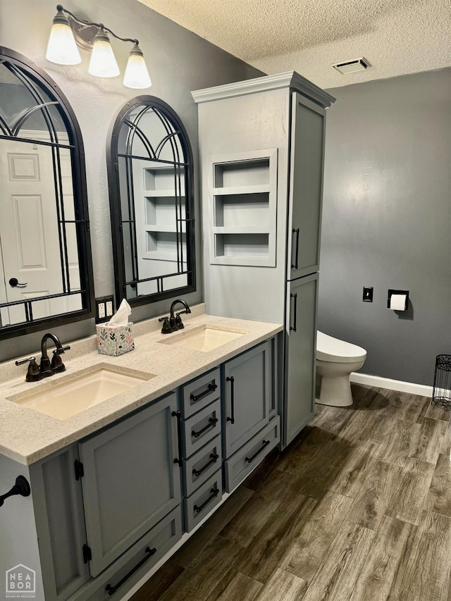 3426 Aggie Rd, Jonesboro, AR 72405 - full bath featuring wood finished floors, double vanity, a textured ceiling, and toilet