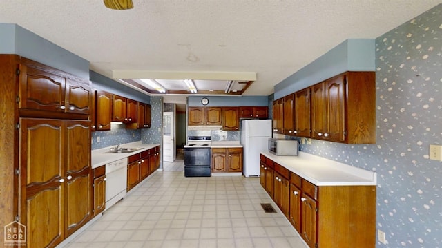 819 Northgate Dr, Osceola, AR 72370 - kitchen featuring a sink, wallpapered walls, white appliances, light floors, and light countertops