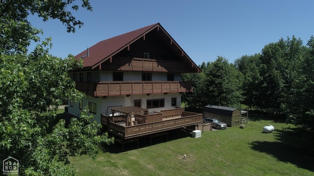  - rear view of property featuring a balcony, stucco siding, and a lawn