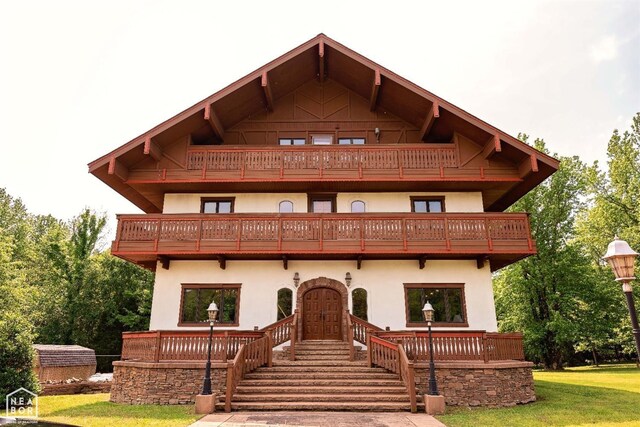 - view of front of home featuring a front yard, a balcony, and stucco siding