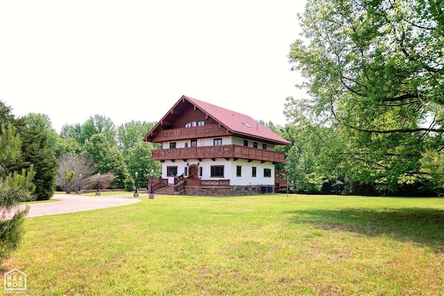 - back of house with a balcony and a lawn