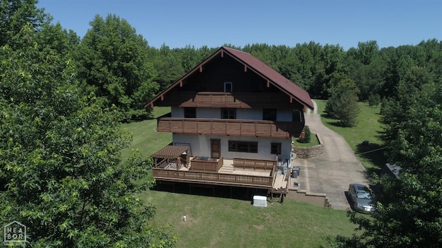 - rear view of house featuring a yard, a deck, a balcony, and a view of trees