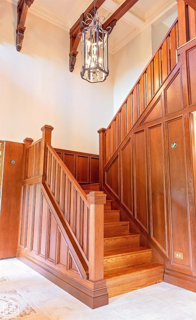 - stairway featuring a chandelier, crown molding, and a decorative wall