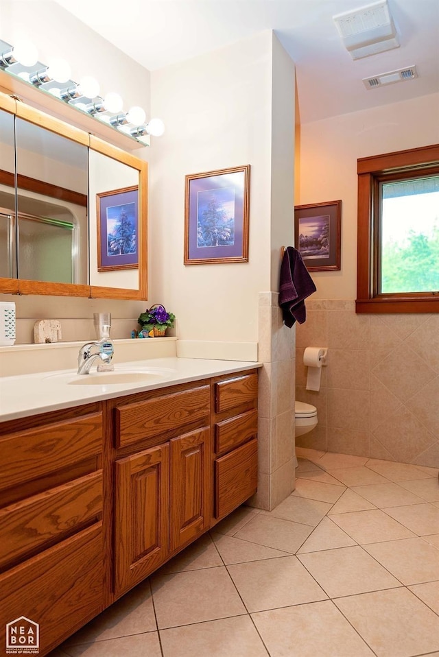  - bathroom featuring vanity, visible vents, toilet, tile walls, and tile patterned floors