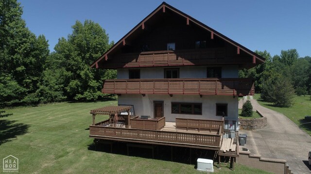  - rear view of property with a yard, stucco siding, a deck, and a balcony