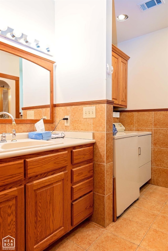  - bathroom featuring washer / clothes dryer, wainscoting, tile patterned flooring, and tile walls