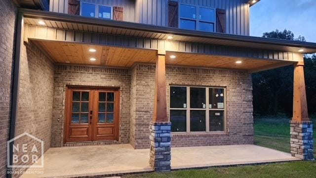 doorway to property with brick siding, french doors, and board and batten siding