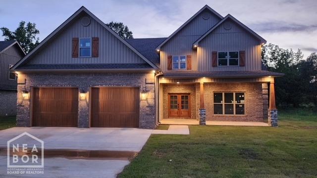craftsman-style home featuring driveway, french doors, a front lawn, brick siding, and a garage