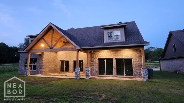 rear view of house featuring brick siding, central AC, a patio, and a lawn