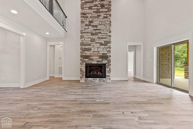 unfurnished living room with a fireplace, light wood finished floors, and baseboards