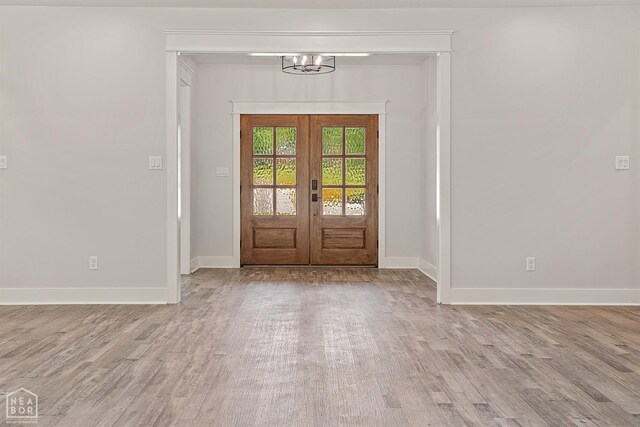 foyer entrance with a chandelier, french doors, baseboards, and wood finished floors