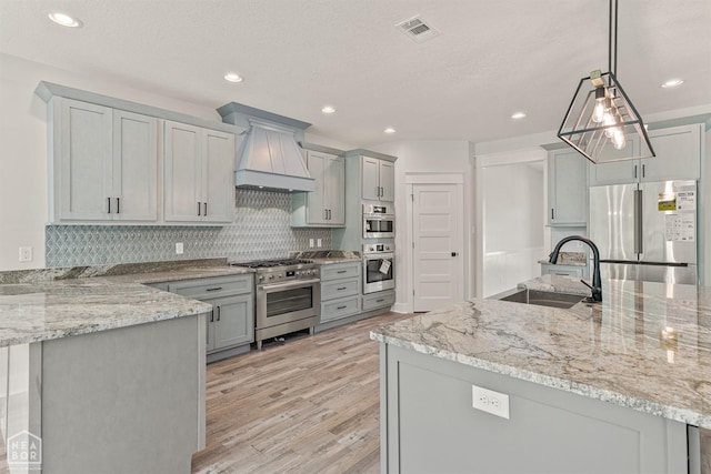 kitchen featuring gray cabinetry, appliances with stainless steel finishes, a sink, and visible vents
