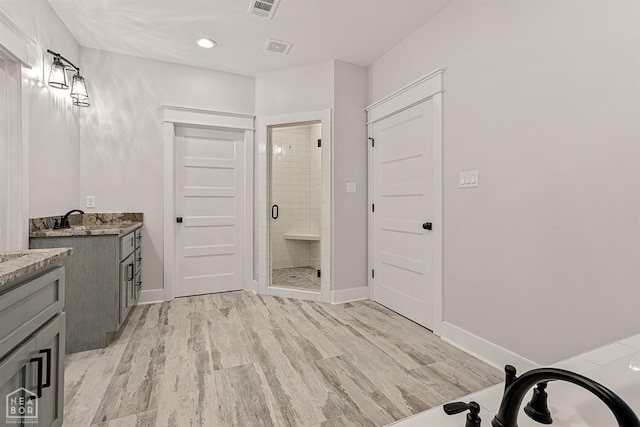 bathroom with visible vents, baseboards, vanity, wood finished floors, and a stall shower