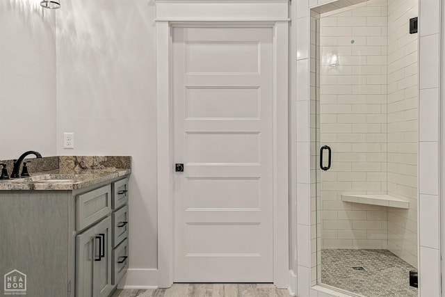 full bath with vanity, a stall shower, and wood finished floors