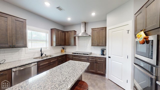 118 E Hills Dr, Bono, AR 72416 - kitchen featuring appliances with stainless steel finishes, wall chimney exhaust hood, backsplash, light stone counters, and recessed lighting