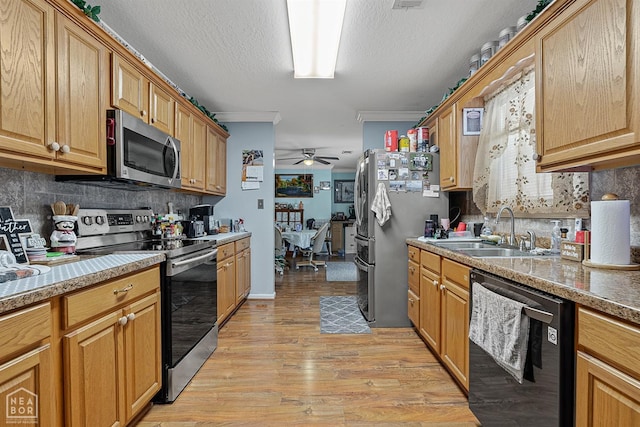 kitchen featuring a sink, decorative backsplash, appliances with stainless steel finishes, and light wood finished floors