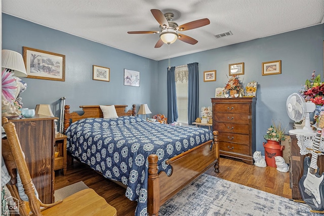 bedroom featuring visible vents, ceiling fan, wood finished floors, and a textured ceiling