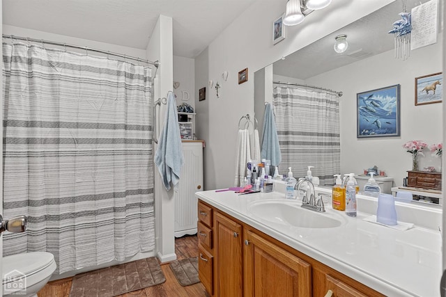 bathroom with visible vents, a shower with curtain, toilet, vanity, and wood finished floors