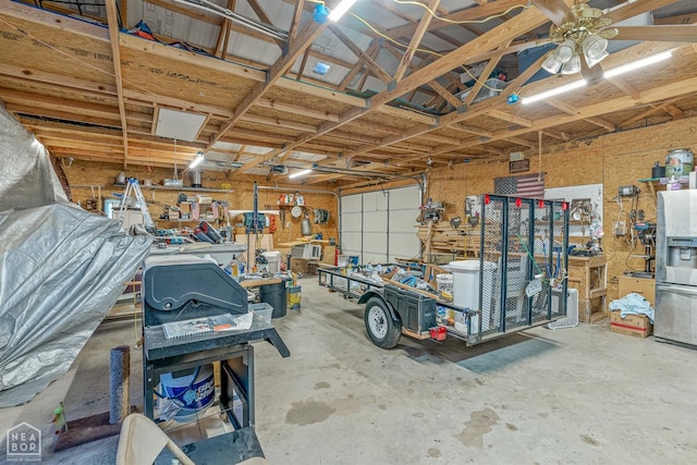 garage with a ceiling fan, stainless steel fridge, and a workshop area