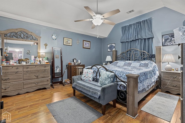 bedroom with a ceiling fan, vaulted ceiling, visible vents, and hardwood / wood-style flooring