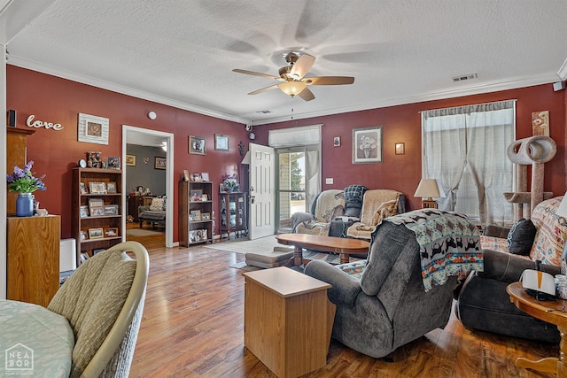 living area featuring crown molding, a textured ceiling, a ceiling fan, visible vents, and wood finished floors