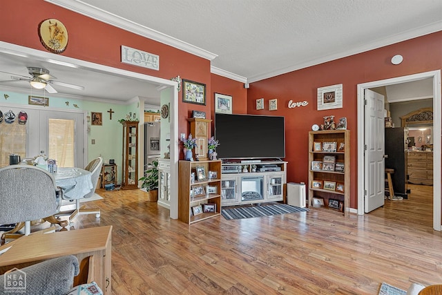 living room with ceiling fan, a textured ceiling, ornamental molding, wood finished floors, and french doors