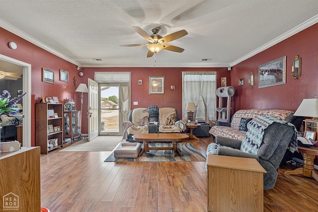 living area featuring visible vents, wood finished floors, ornamental molding, and ceiling fan