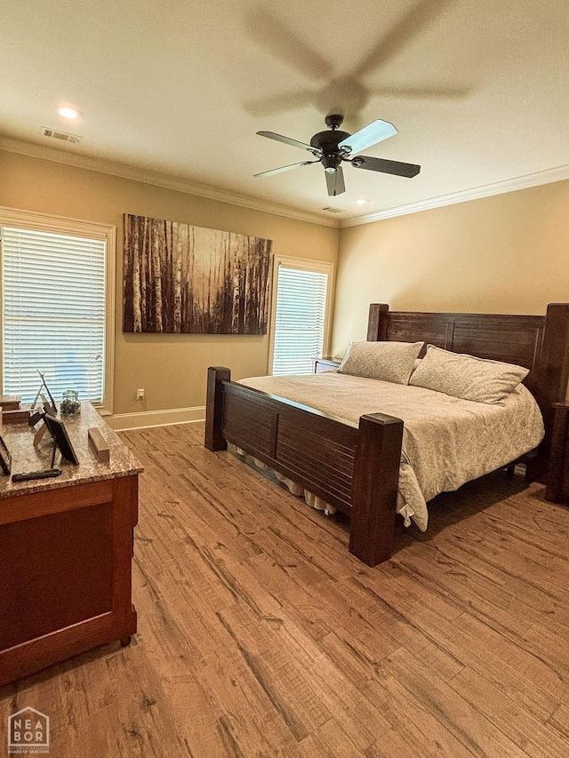 bedroom featuring visible vents, ornamental molding, baseboards, and wood finished floors