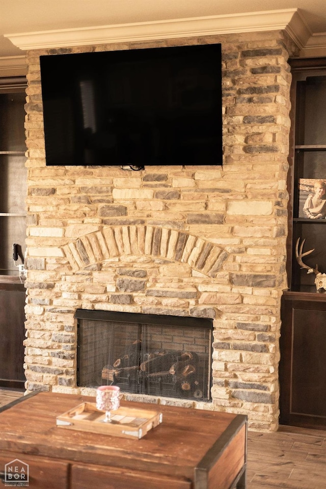 details with crown molding, a stone fireplace, and wood finished floors