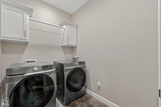 washroom featuring baseboards, washing machine and clothes dryer, and cabinet space