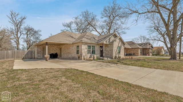view of front of house featuring brick siding, a front lawn, and fence