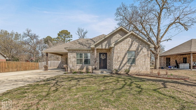 view of front facade featuring concrete driveway, a carport, a front yard, brick siding, and fence