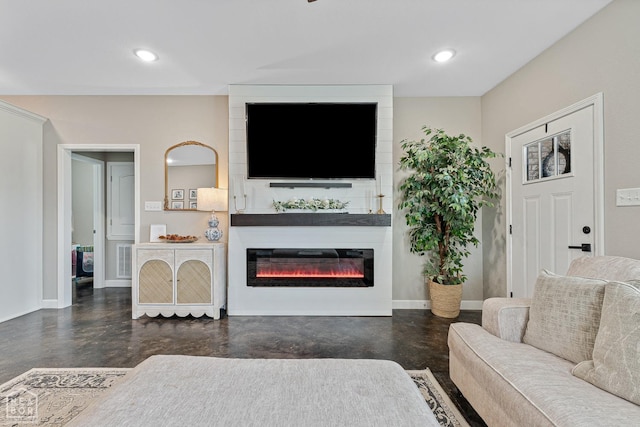 living room featuring concrete flooring, a glass covered fireplace, visible vents, recessed lighting, and baseboards