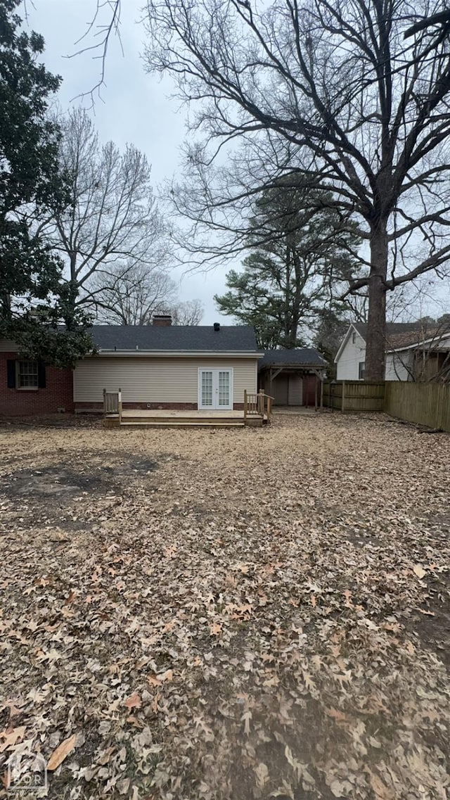 621 W Thomas Ave, Jonesboro, AR 72401 - back of property with french doors, a wooden deck, fence, and a chimney